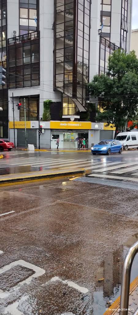 Fachada exterior del Estudio Contable y Jurídico Flores de la Dra. Rivero sobre Av. Rivadavia en Buenos Aires, con ventanales cálidos y carpintería de bronce elegante.